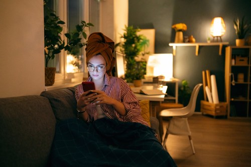 Young woman using phone during the relaxing evening at home.